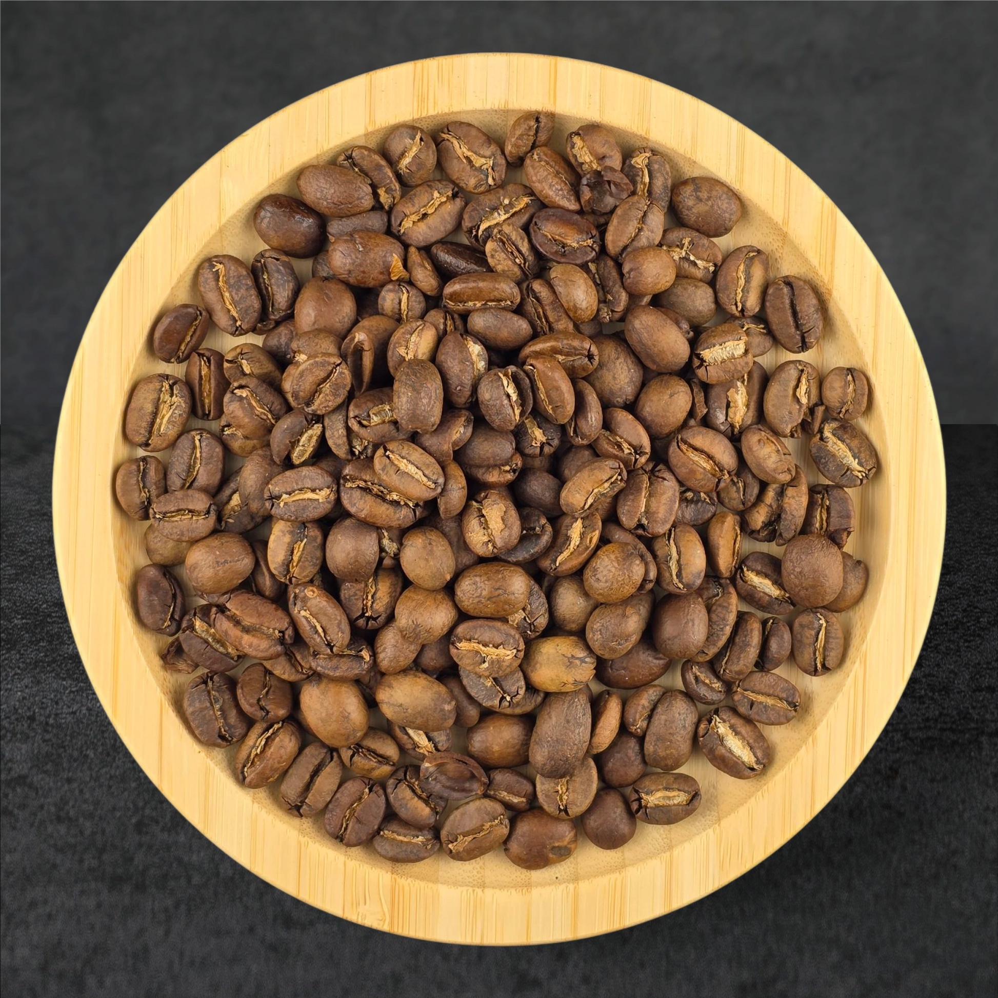 Roasted coffee beans on a wooden plate with a dark background