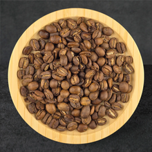 Roasted coffee beans on a wooden plate with a dark background