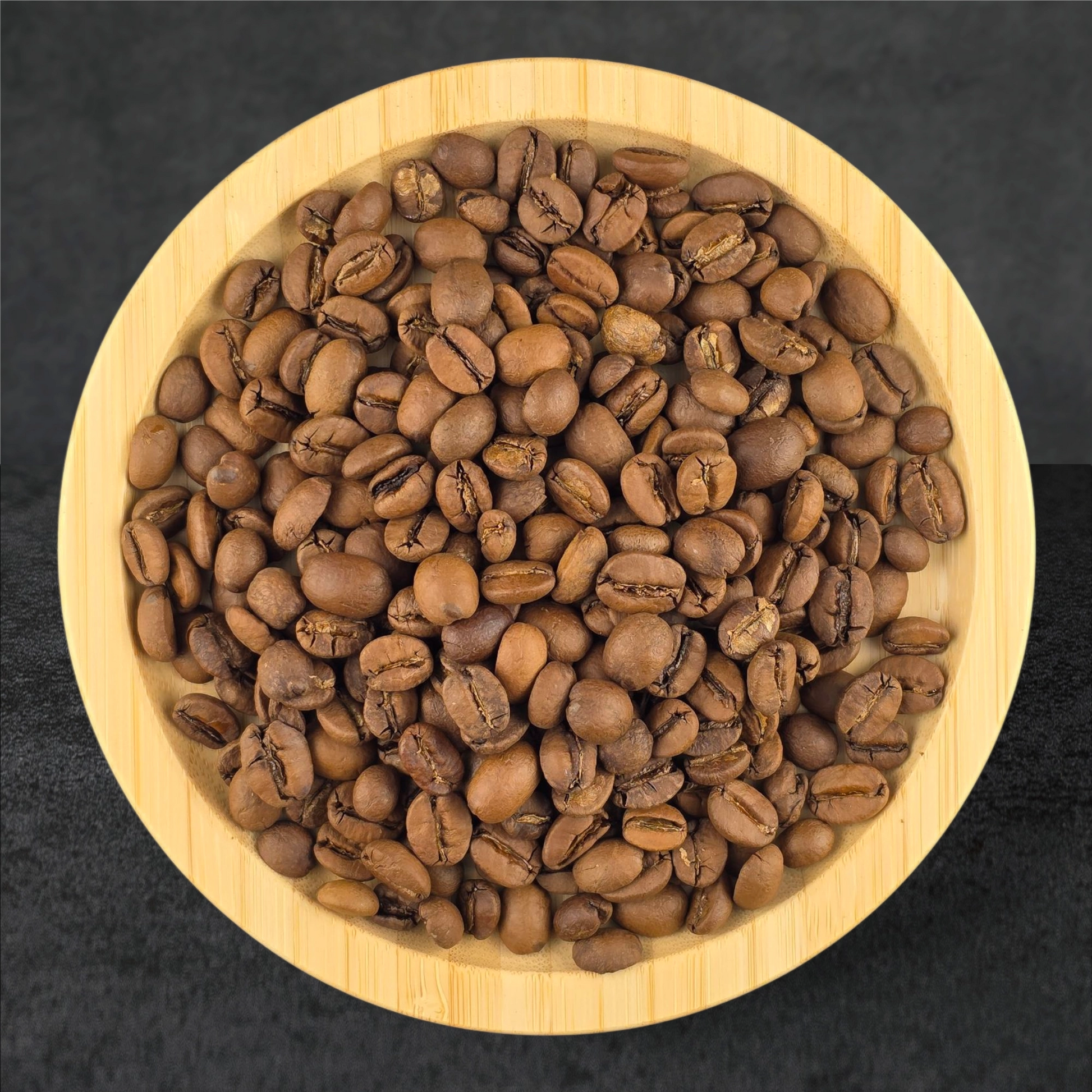 Wooden bowl filled with coffee beans on a dark background