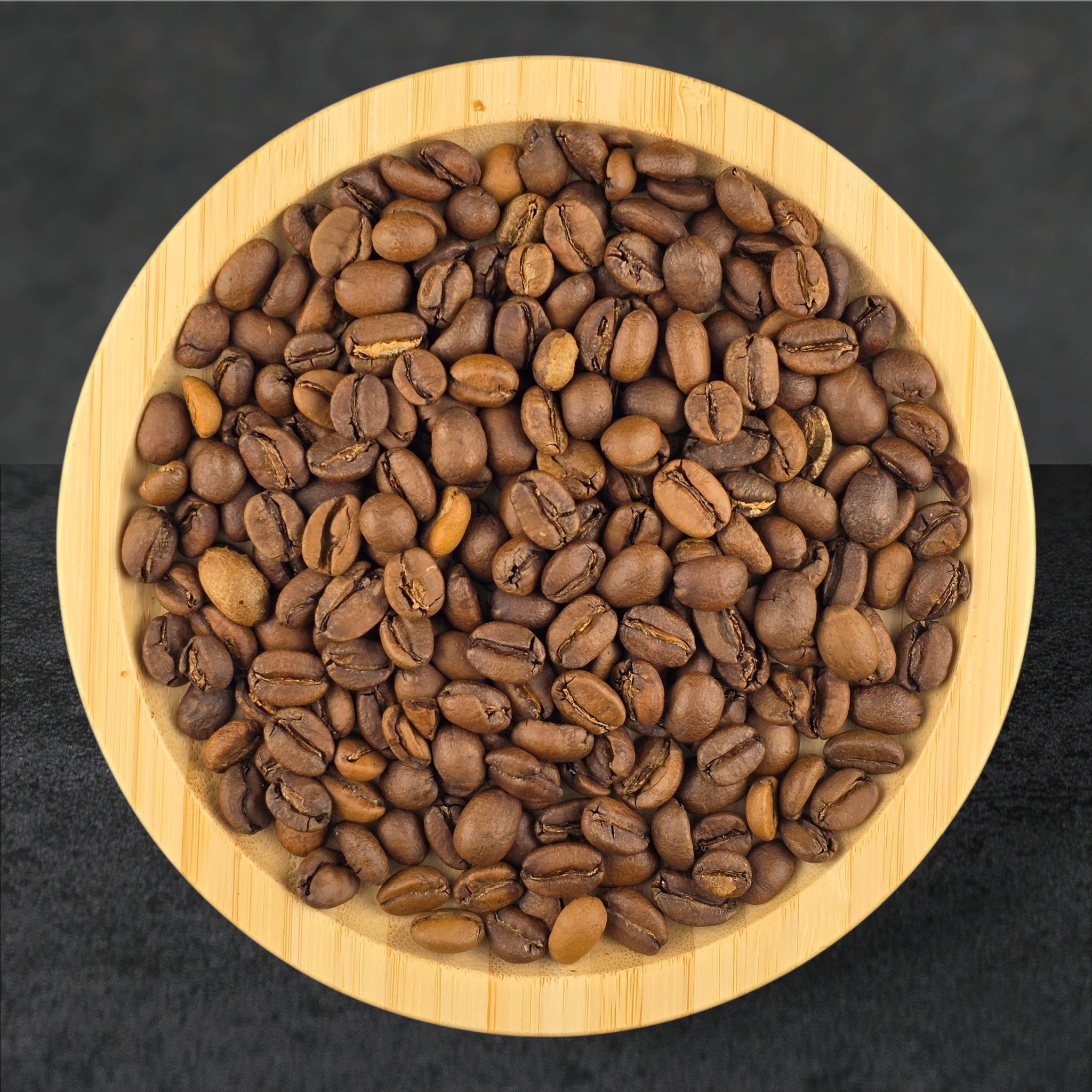 Coffee beans in a wooden bowl on a dark background