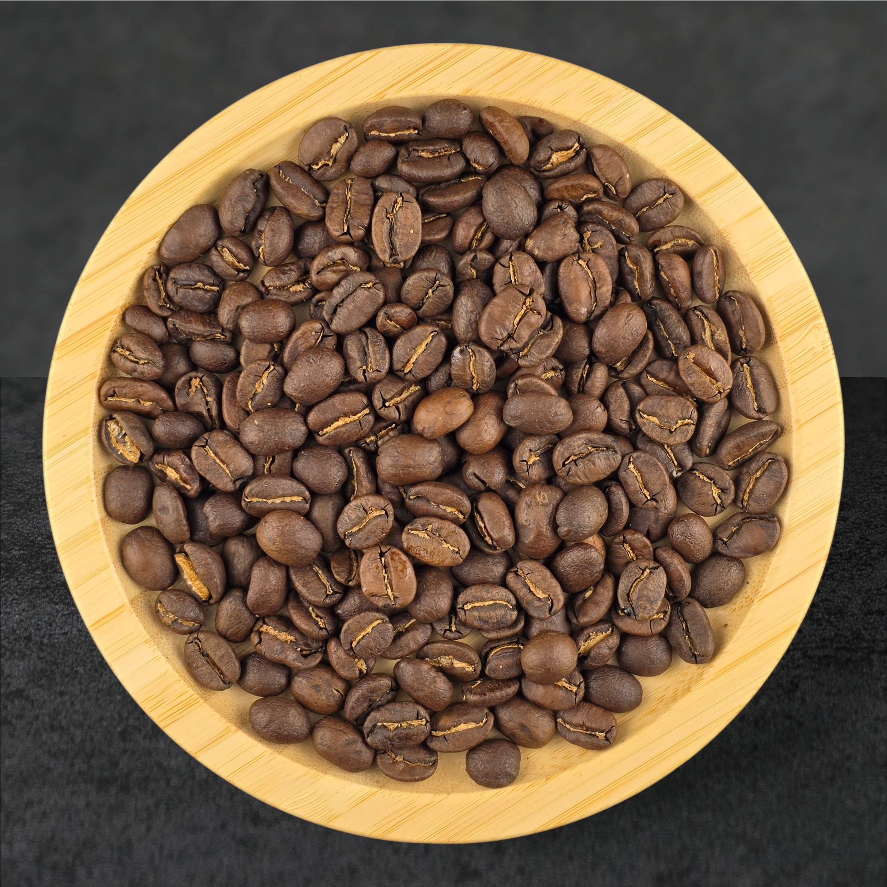 Coffee beans in a wooden bowl on a dark background