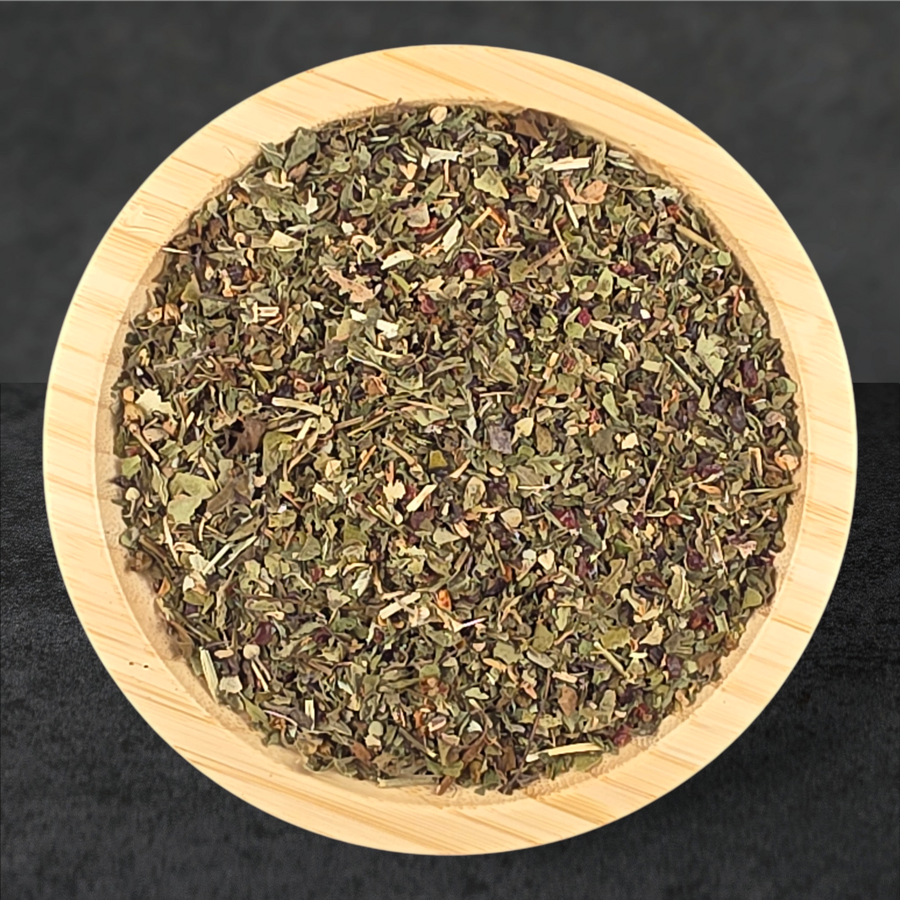 Wooden bowl filled with dried herbs on a black background