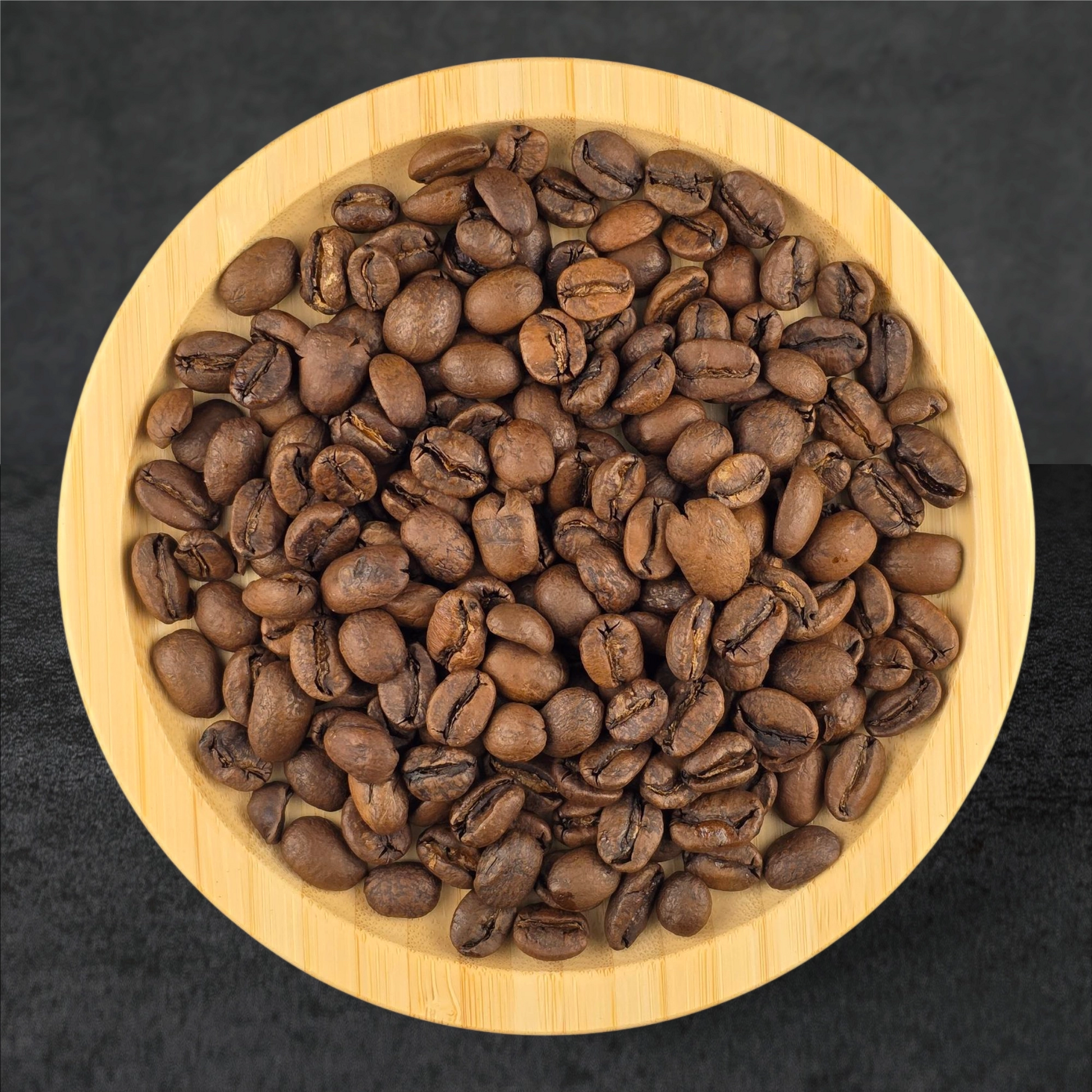 Roasted coffee beans in a wooden bowl on a dark background