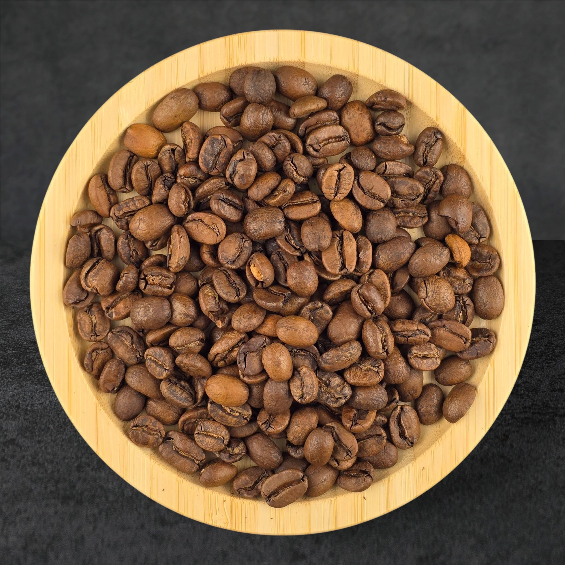 Roasted coffee beans in a wooden bowl on a dark background