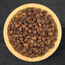 Roasted coffee beans in a wooden bowl on a dark background