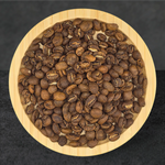 Roasted coffee beans in a wooden bowl on a dark background