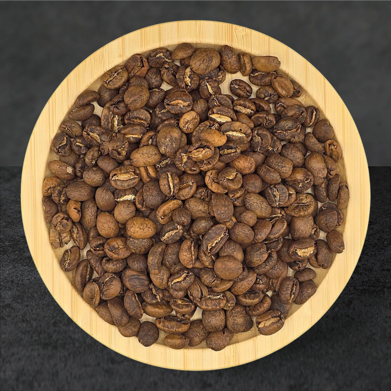 Roasted coffee beans in a wooden bowl on a dark background